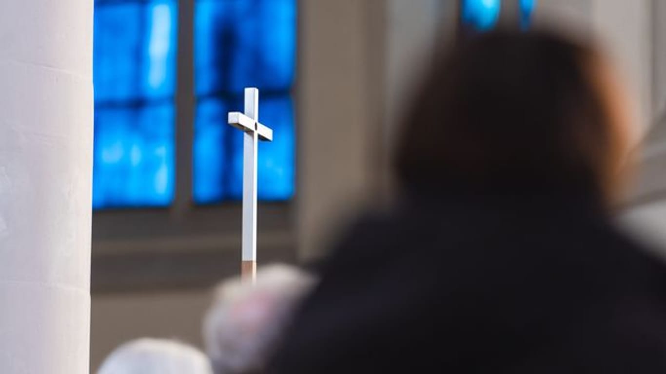 Eine Person schaut auf ein Kreuz (Symbolbild): Erneut ist ein Pfarrer mit Missbrauchsvorwürfen konfrontiert. Die Diözese Rottenburg-Stuttgart reagiert.