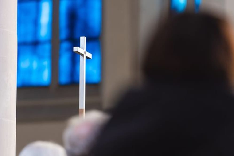 Eine Person schaut auf ein Kreuz (Symbolbild): Erneut ist ein Pfarrer mit Missbrauchsvorwürfen konfrontiert. Die Diözese Rottenburg-Stuttgart reagiert.