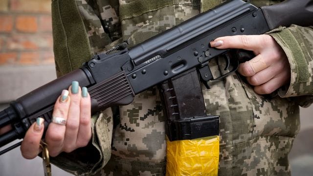 Eine bewaffnete Zivilschützerin mit einem Kalaschnikow-Sturmgewehr in Charkiw.