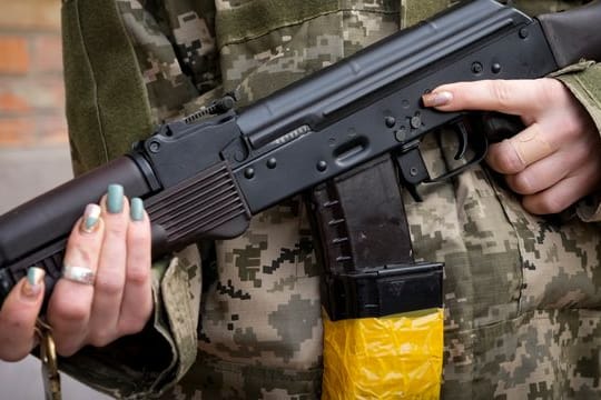 Eine bewaffnete Zivilschützerin mit einem Kalaschnikow-Sturmgewehr in Charkiw.