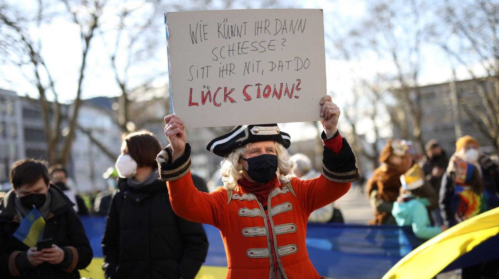 Solidaritätsbekundung mit den Opfern des russischen Krieges: "Wie könnt ihr denn schießen? Seht ihr nicht, dass da Leute stehen?", steht auf dem Schild dieses verkleideten Mannes.