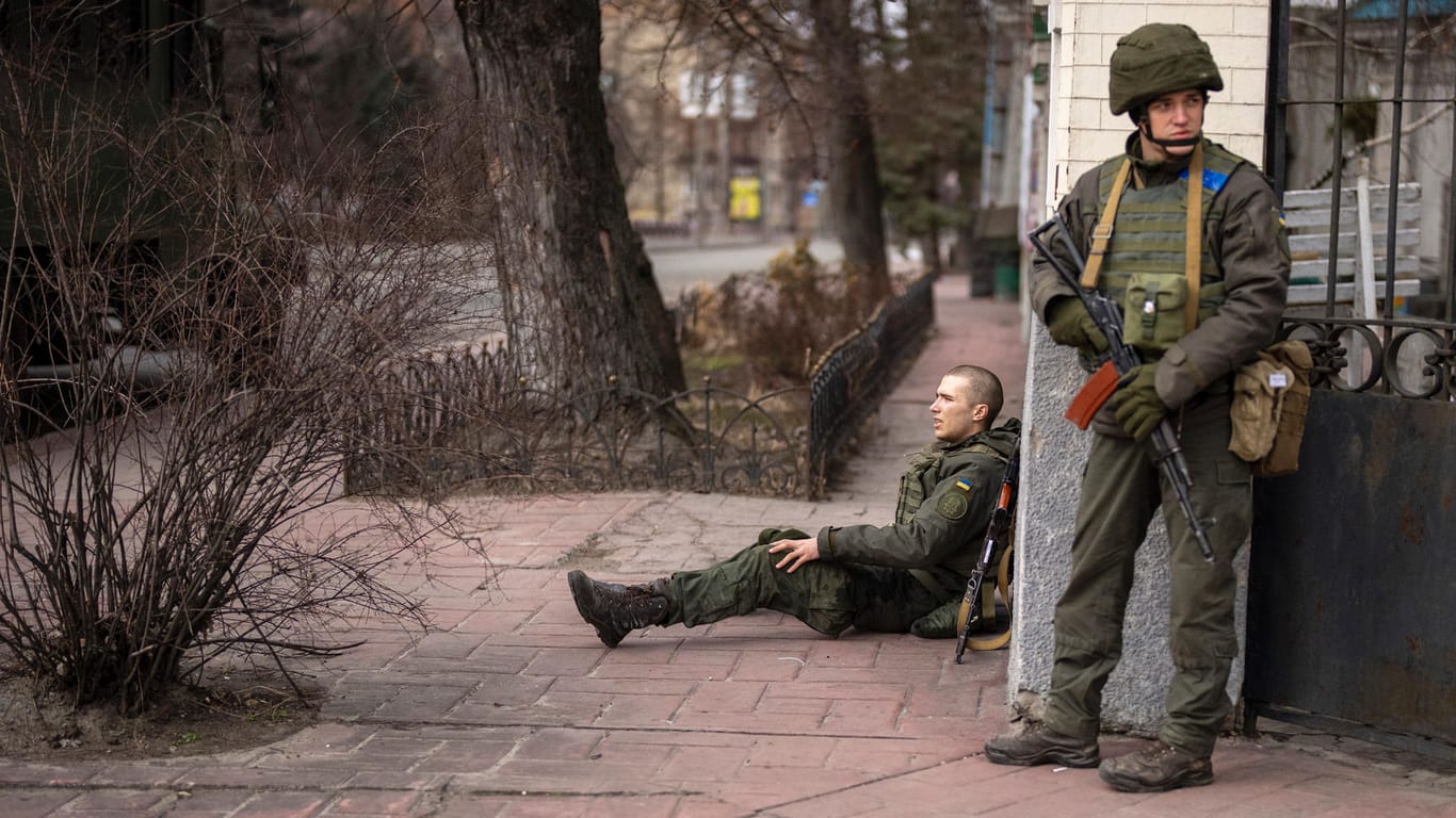 Ein ukrainischer Soldat sitzt nach einem Feuergefecht in Kiew verletzt auf dem Boden: In der Hauptstadt sind immer wieder Explosionen und Schüsse zu hören.