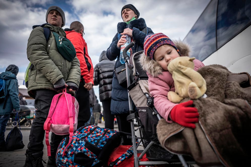 Ukrainer flüchten aus ihrer Heimat: Diese Familie wartet nach ihrem Grenzübertritt in Polen auf einen Bus, der sie zu einer Übergangsunterkunft bringt.