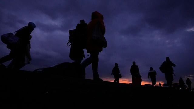 Flüchtlinge, die vor dem Konflikt in der benachbarten Ukraine geflohen sind, gehen mit ihrem Gepäck eine Straße in Polen entlang.