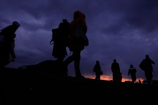 Flüchtlinge, die vor dem Konflikt in der benachbarten Ukraine geflohen sind, gehen mit ihrem Gepäck eine Straße in Polen entlang.