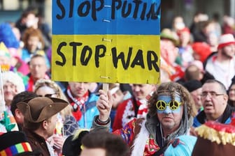 "Stop Putin": Ein Karnevalist verfolgt mit einem Transparent das traditionelle Funken-Biwak.