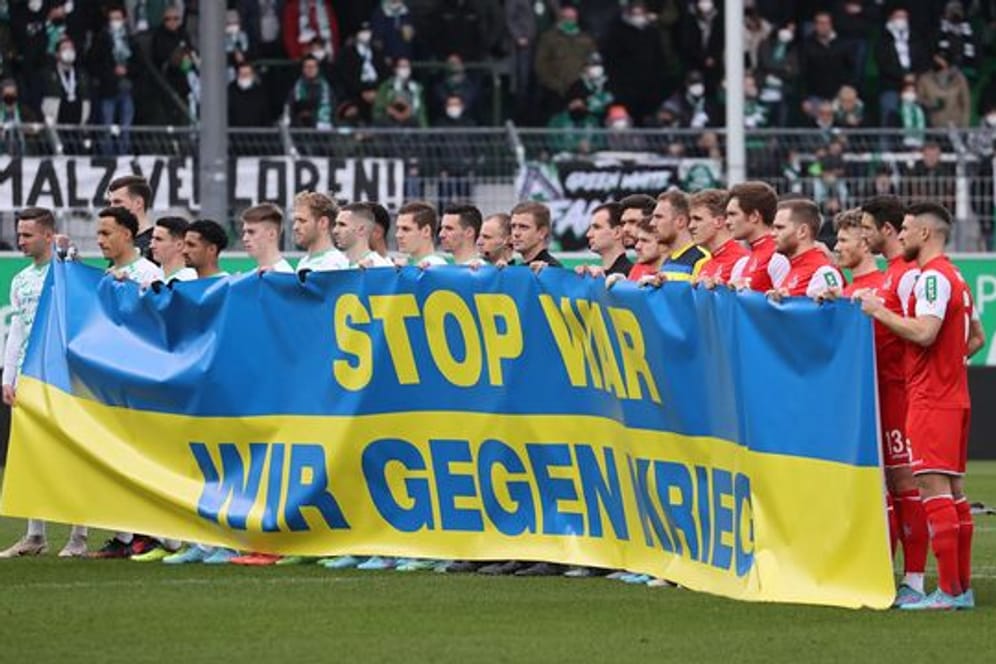 Fürther und Kölner Spieler halten zu Spielbeginn ein Transparent in den ukrainischen Farben mit der Aufschrift "Stop War.
