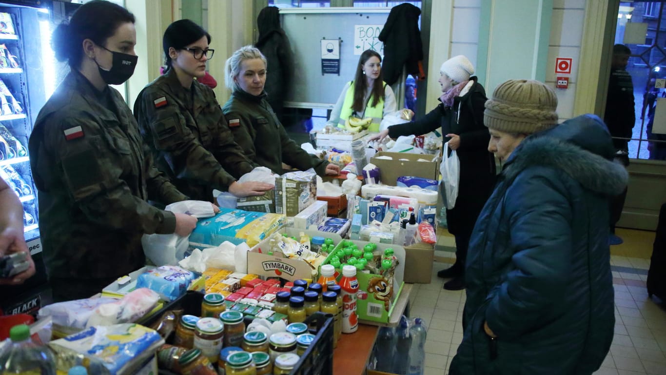 In der Bahnhofshalle bieten polnische Helferinnen den Geflüchteten Lebensmittel und Kaffee an.