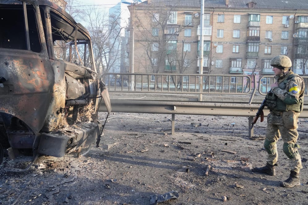 Ein ukrainischer Soldat geht an den Trümmern eines brennenden Militärlastwagens vorbei