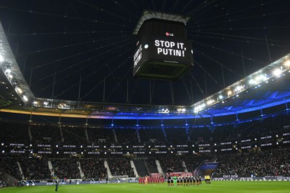 Die Mannschaften von Eintracht Frankfurt und dem FC Bayern München stehen vor dem Spiel während einer Schweigeminute für die Ukraine zusammen.