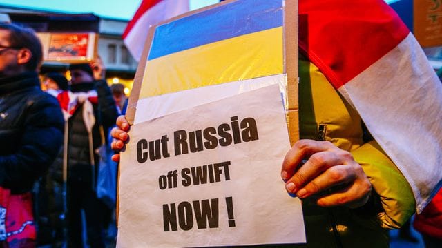 Ein Demonstrant hält ein Schild mit der ukrainischen Flagge und der Aufschrift "Russland jetzt abschneiden!".