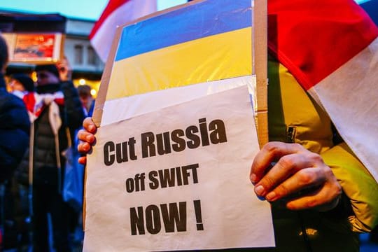 Ein Demonstrant hält ein Schild mit der ukrainischen Flagge und der Aufschrift "Russland jetzt abschneiden!".