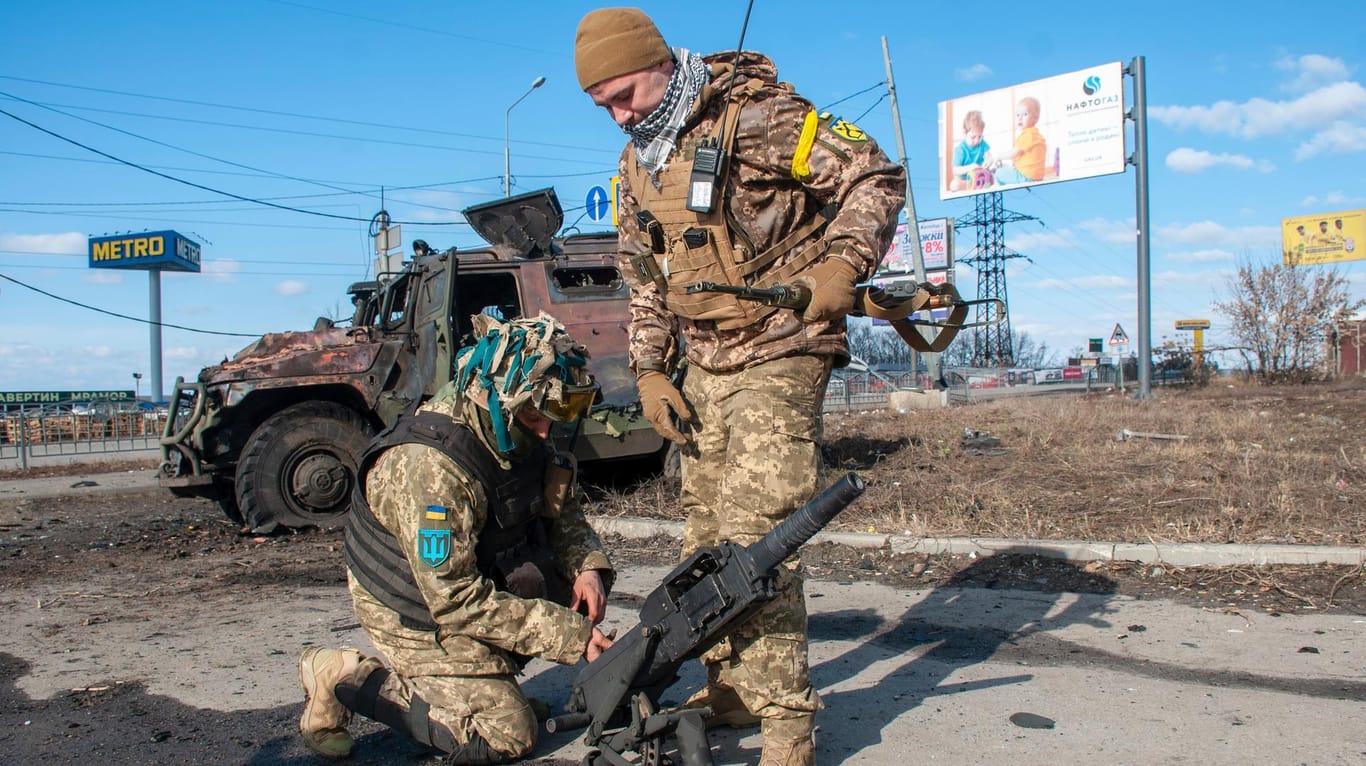 Ukrainische Soldaten hantieren mit Ausrüstung aus einem beschädigten Militärfahrzeug: Die Ukraine bestätigt Verhandlungen mit Russland.