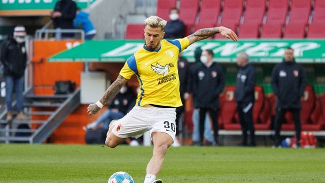 Augsburgs Niklas Dorsch wärmt sich in einem Trikot in den Landesfarben der Ukraine auf. Augsburgs Niklas Dorsch wärmt sich in einem Trikot in den Landesfarben der Ukraine auf.