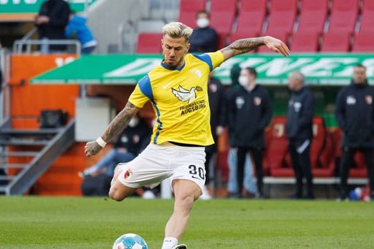Augsburgs Niklas Dorsch wärmt sich in einem Trikot in den Landesfarben der Ukraine auf.
