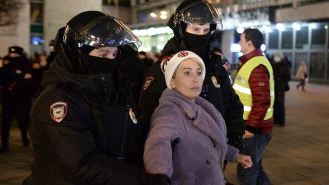 Zwei Polizisten nehmen eine Frau während einer Demonstration in Moskau gegen die russische Invasion in die Ukraine fest.