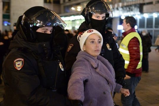 Zwei Polizisten nehmen eine Frau während einer Demonstration in Moskau gegen die russische Invasion in die Ukraine fest.