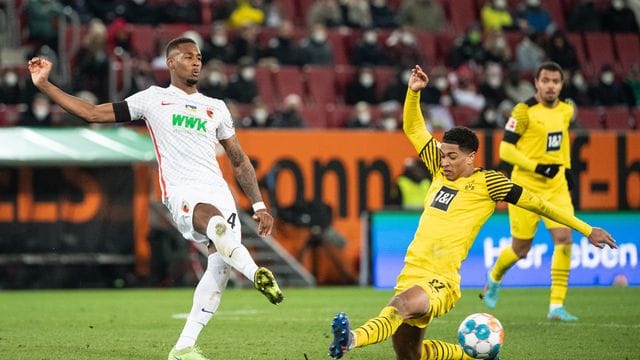 Dortmunds Jude Bellingham (r) versucht den Schuss des Augsburgers Reece Oxford zu blocken.