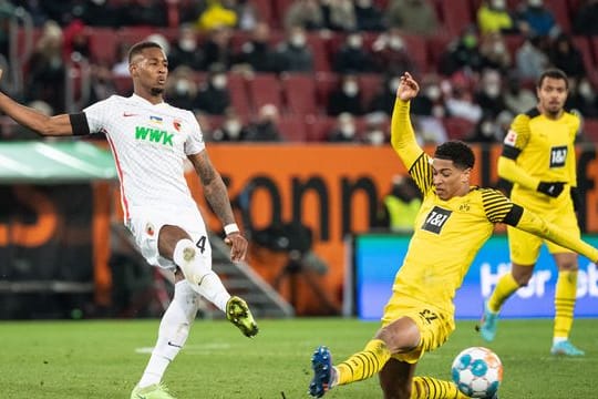 Dortmunds Jude Bellingham (r) versucht den Schuss des Augsburgers Reece Oxford zu blocken.