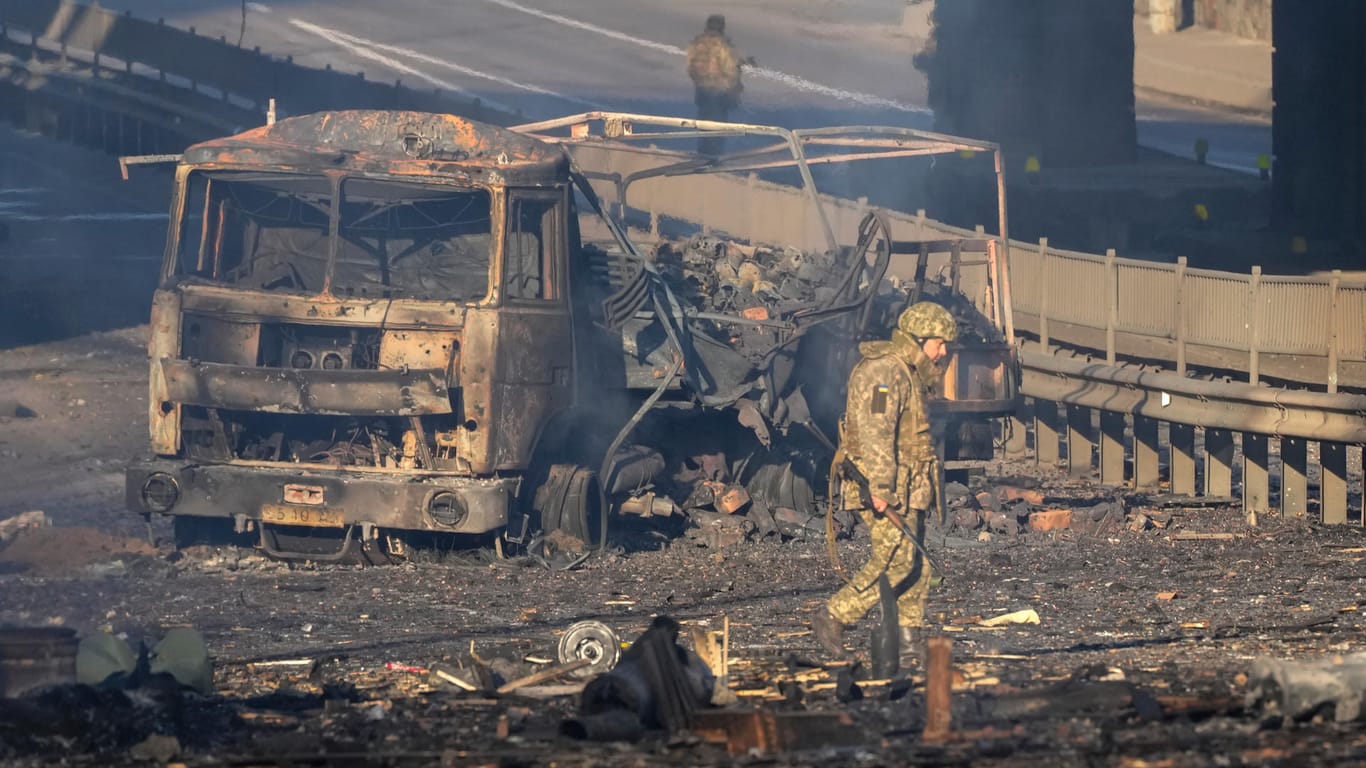 Ukrainischer Soldat vor einem ausgebrannten russischen Militärlaster. Ukraine-Konflikt