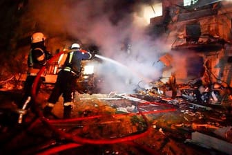 Feuerwehrleute löschen die Schäden an einem Gebäude nach einem Raketenangriff in Kiew.