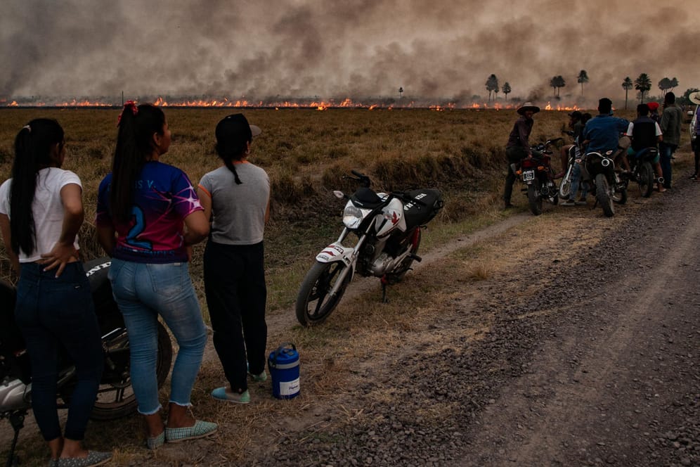 Anwohner beobachten Feuerwehrmänner und Freiwillige, die versuchen einen großen Waldbrand in Corrientes, Argentinien, zu löschen: Der Weltklimarat der UN beleuchtet in seinem neuesten Bericht die konkreten Gefahren der Klimakrise für Mensch und Natur.