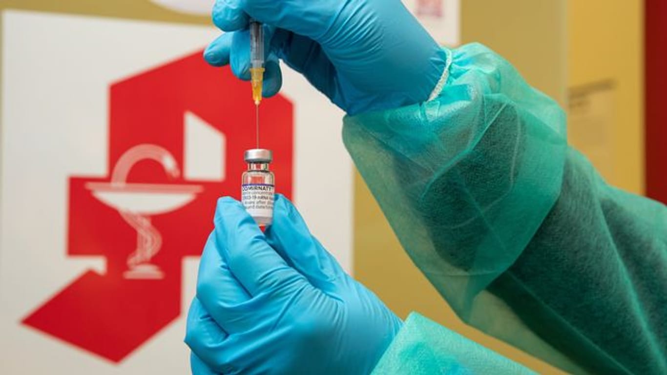 Eine Apothekerin zieht den Impfstoff Comirnaty vom Hersteller Biontech / Pfizer mit einer Spritze auf.
