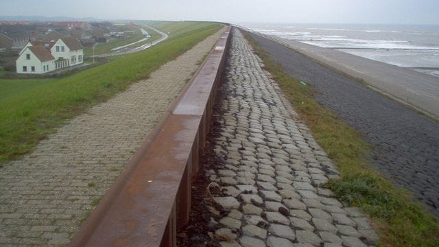 Ein Ort liegt an einem Deich hinter einem Strand in den Niederlanden. Ein Ort liegt an einem Deich hinter einem Strand in den Niederlanden.