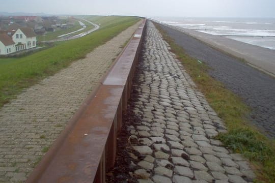 Ein Ort liegt an einem Deich hinter einem Strand in den Niederlanden.