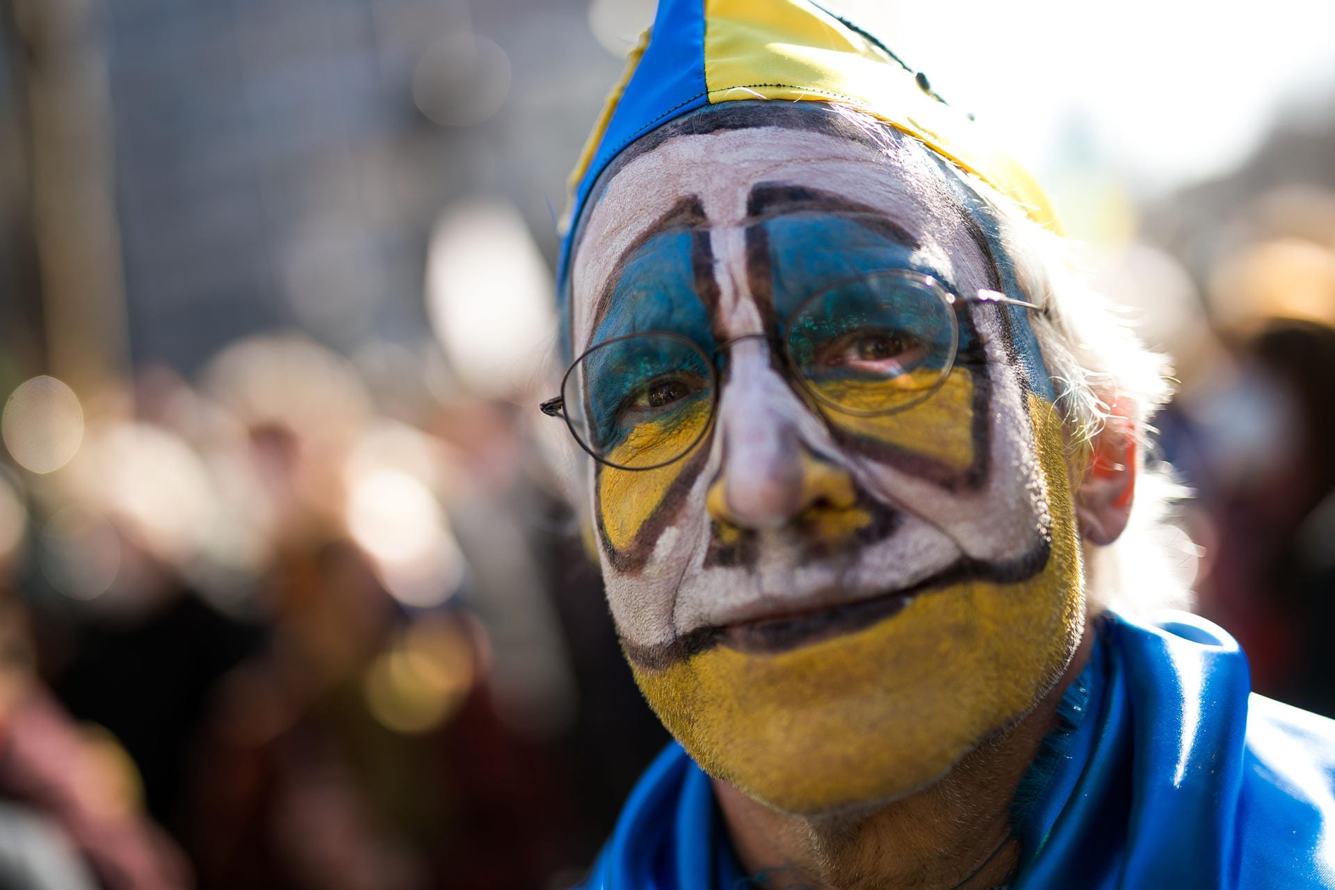 Kostümiert und zugleich positioniert: Dieser Karnevalist trägt die Farben der Ukraine im Gesicht.