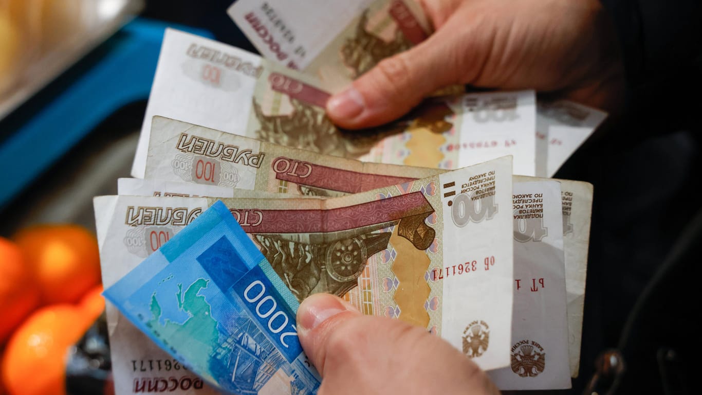 Eine Person hält Rubel-Scheine in der Hand (Symbolbild): Wegen der Sanktionen fürchten viele Russen um ihr Geld, doch einen Transfer ins Ausland hat Putin nun verboten.