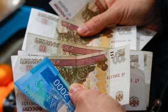 Eine Person hält Rubel-Scheine in der Hand (Symbolbild): Wegen der Sanktionen fürchten viele Russen um ihr Geld, doch einen Transfer ins Ausland hat Putin nun verboten.