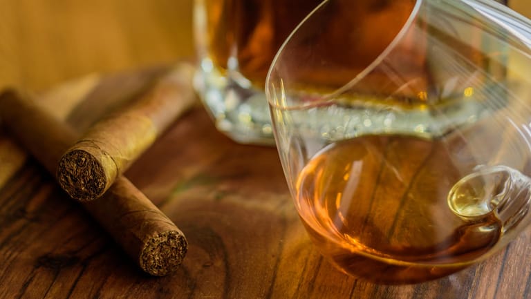 Ein Glas Rum mit Flasche und zwei Zigarren