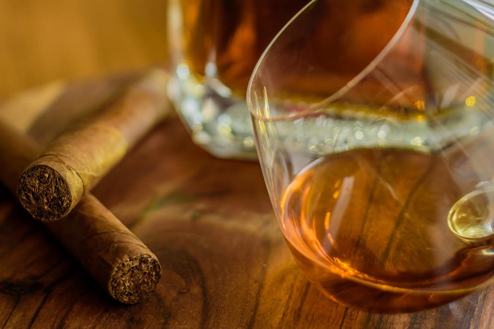 Ein Glas Rum mit Flasche und zwei Zigarren