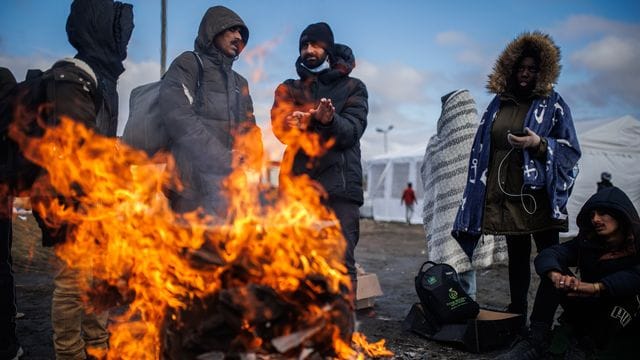 Mehrere Menschen wärmen sich an einem Feuer am Grenzübergang zwischen Polen und der Ukraine.