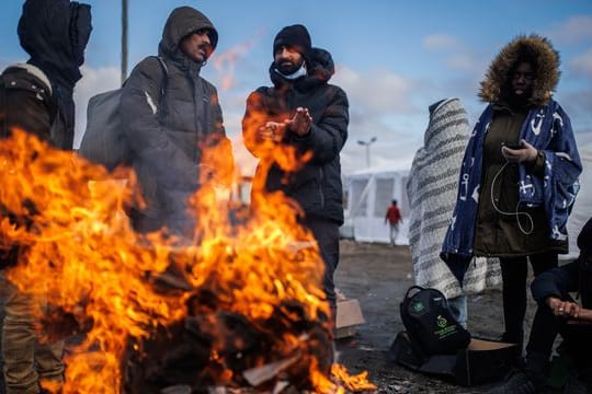 Mehrere Menschen wärmen sich an einem Feuer am Grenzübergang zwischen Polen und der Ukraine.