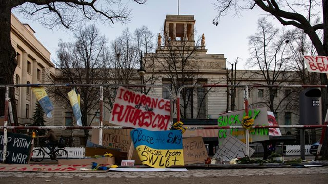 An den Absperrgittern vor der russischen Botschaft in Berlin haben Menschen Plakate angebracht.