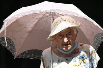Eine alte Dame schützt sich vor der Sonne: Die Klimakrise ist vor allem ein gesundheitliches Risiko, sagt Eckart von Hirschhausen. Man müsse die Menschheit retten, nicht das Klima.
