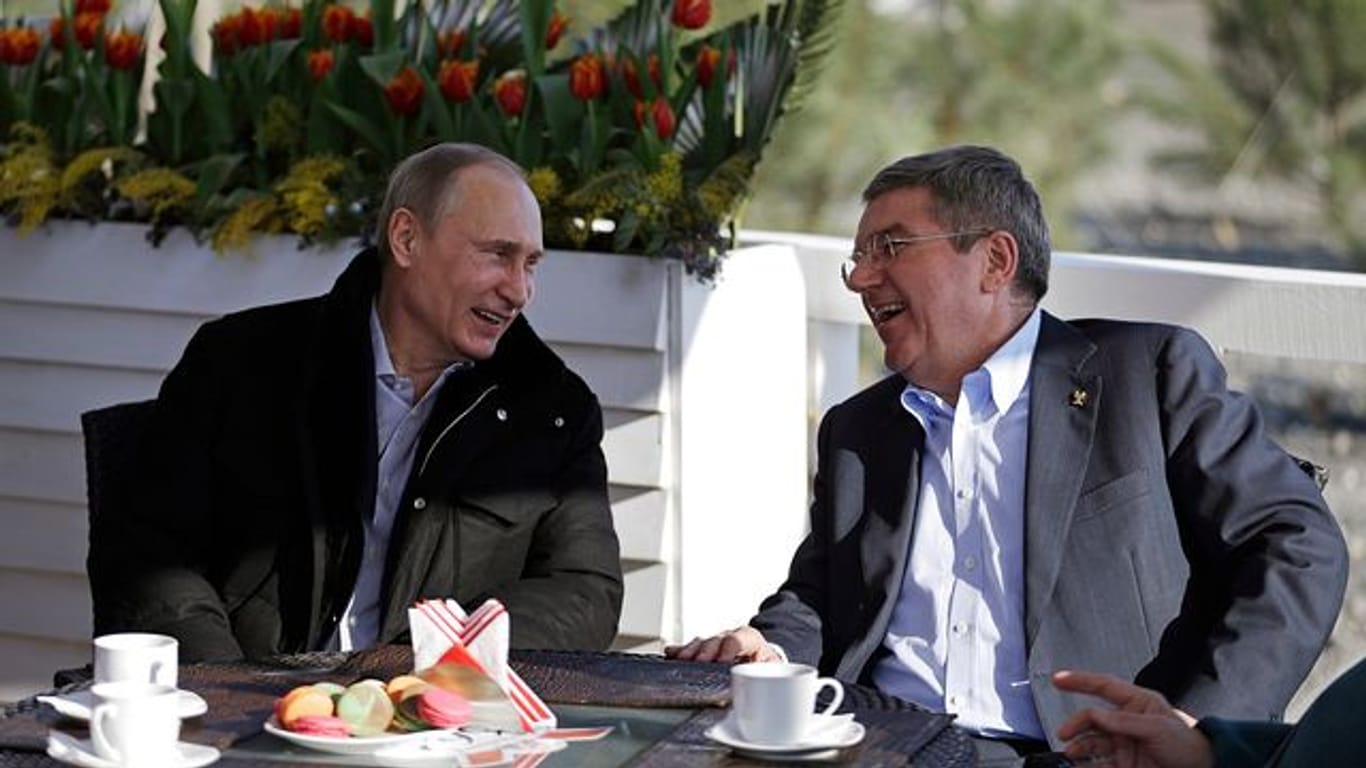 Der russische Präsident Wladimir Putin (l) und der IOC-Präsident Thomas Bach unterhalten sich in einem Cafe an der Promenade am schwarzen Meer während der Olympischen Spiele 2014 in Sotschi.