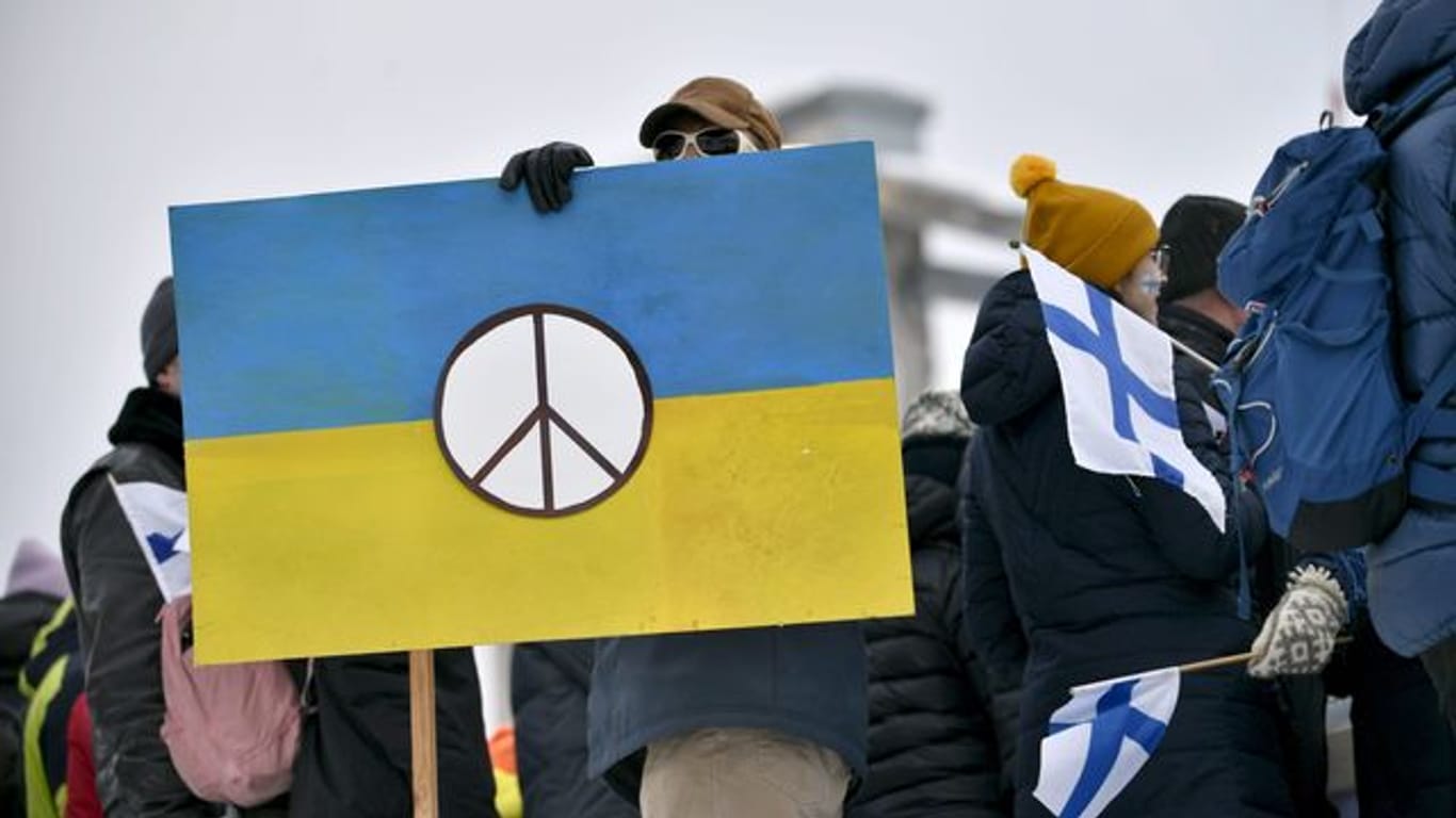 Ukraine-Unterstützer halten beim FIS Weltcup ein blau-gelbes Schild.