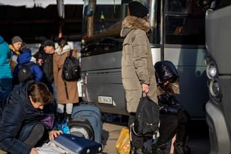 Ukrainische Bürger bereiten sich an einem Bahnhof im Westen der Ukraine vor, in einen Bus nach Polen einzusteigen.
