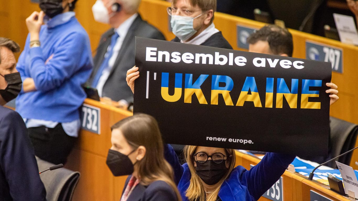 Eine Abgeordnete hält ein Schild mit der Aufschrift "Ensemble avec Ukraine" (dt. "Gemeinsam mit der Ukraine") vor einer Plenarsitzung des Europäischen Parlaments.