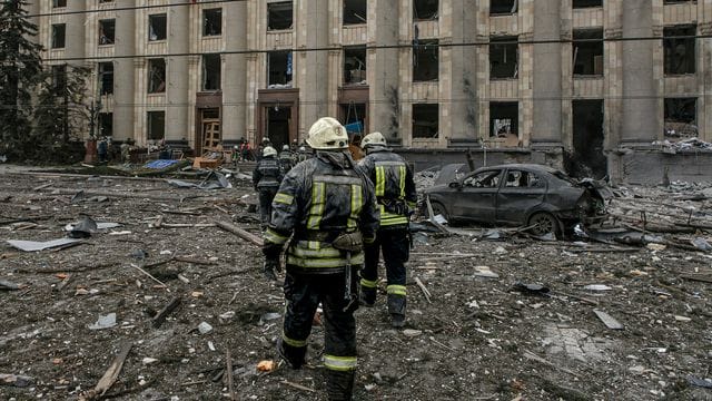 Ukrainische Rettungskräfte arbeiten vor dem beschädigten Rathausgebäude in Charkiw nach dem russischen Beschuss.