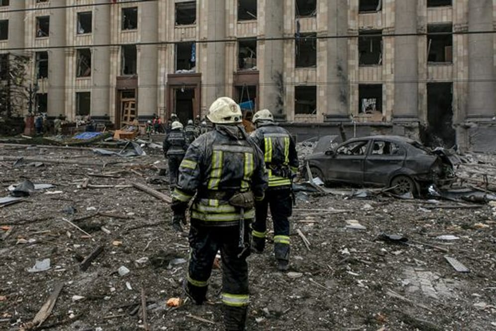Ukrainische Rettungskräfte arbeiten vor dem beschädigten Rathausgebäude in Charkiw nach dem russischen Beschuss.