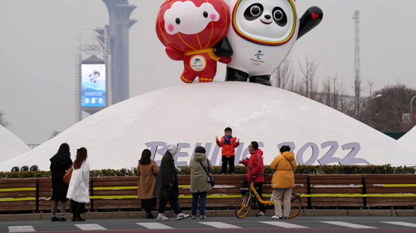 Besucher fotografieren sich vor den Maskottchen für die Olympischen und Paralympischen Winterspiele 2022.
