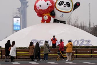 Besucher fotografieren sich vor den Maskottchen für die Olympischen und Paralympischen Winterspiele 2022.