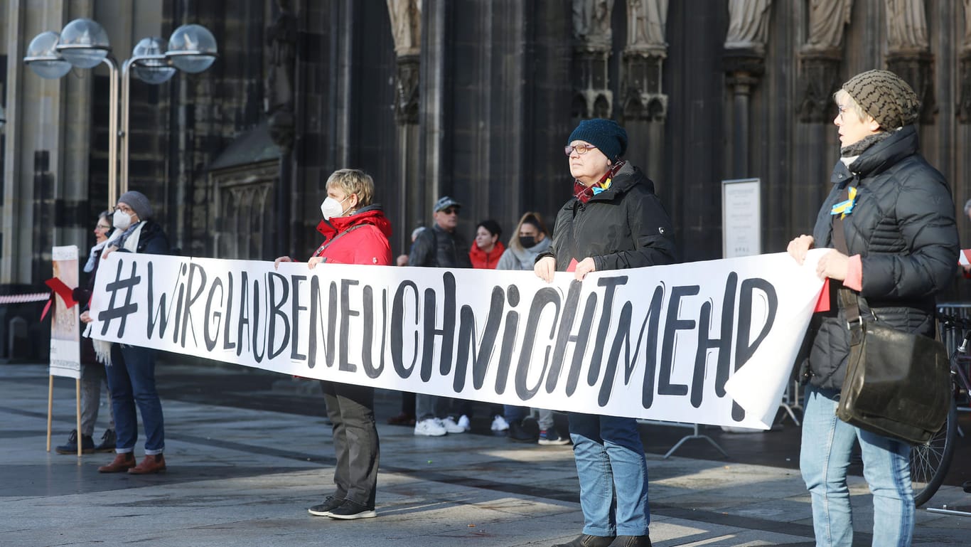 Mitglieder der kirchenkritischen Bewegung Maria 2.0 protestieren mit einem Transparent mit der Aufschrift "#Wir glaubenEuchnichtmehrl" vor dem Dom: Die vorläufige Rückkehr Woelkis stößt auf Protest in der Glaubensgemeinschaft.