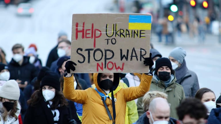 Eine Perso hält während eines Demonstrationszuges in Hamburg ein Schild mit der Aufschrift: "Help Ukraine to stop war now"