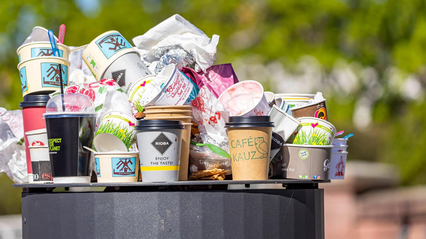 Eis- und Kaffeebecher türmen sich auf einem Mülleimer (Symbolbild): Durch vermehrte Essensbestellungen, To-Go-Getränke und Onlineshopping wachsen die Müllberge in den Städten immer weiter.