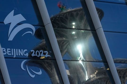 Der Pekinger Olympiaturm spiegelt sich in den Fenstern des Main Media Centers mit dem Logo der Winter-Paralympics 2022.